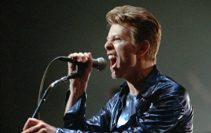 David Bowie canta em um microfone.